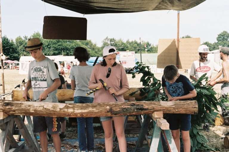 Une jeune femme travaille le bois à la ZAD de Notre-Dames-Des-Landes lors d'un weekend de construction collective à l'été 2019. Photographie : June Loper pour Radio Parleur