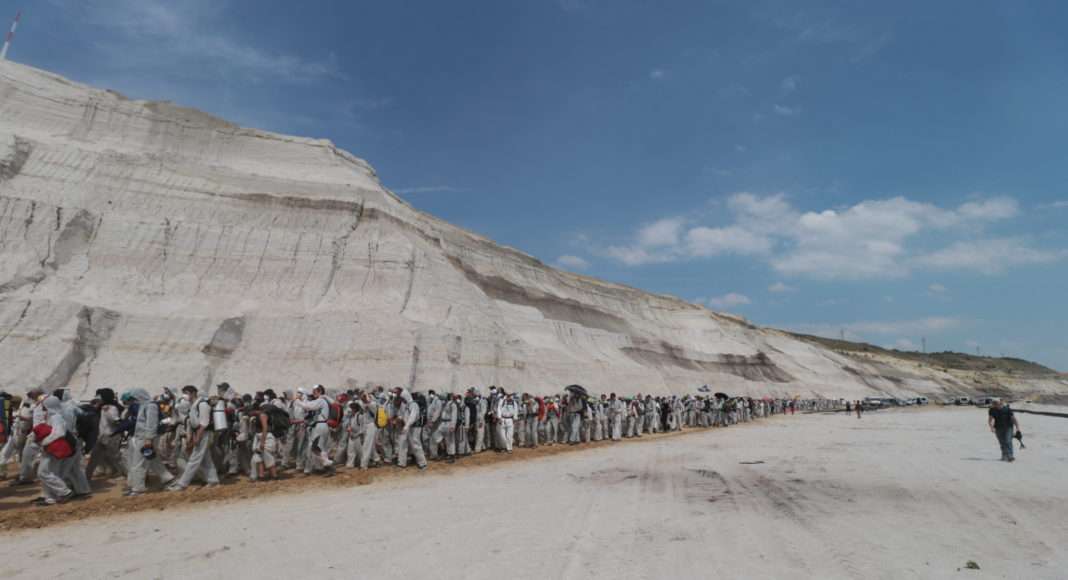 Les activistes d'Ende Gelände progressent dans le paysage désertique et abyssal de la mine de charbon. Ils se dirigent vers le bas de cette vallée artificielle en contournant les petits barrages sur leur route.