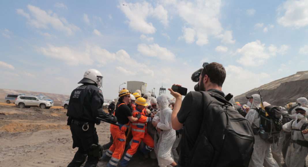 Les activistes sont stoppés alors qu'ils atteignent le niveau de l'excavatrice par un mélange de policiers et d'employés vếtus d'une tenue RWE, la compagnie qui possède la mine. La riposte est brutale, et plusieurs d'entre eux devront être soignés par les médecins qui suivent la manifestations.
